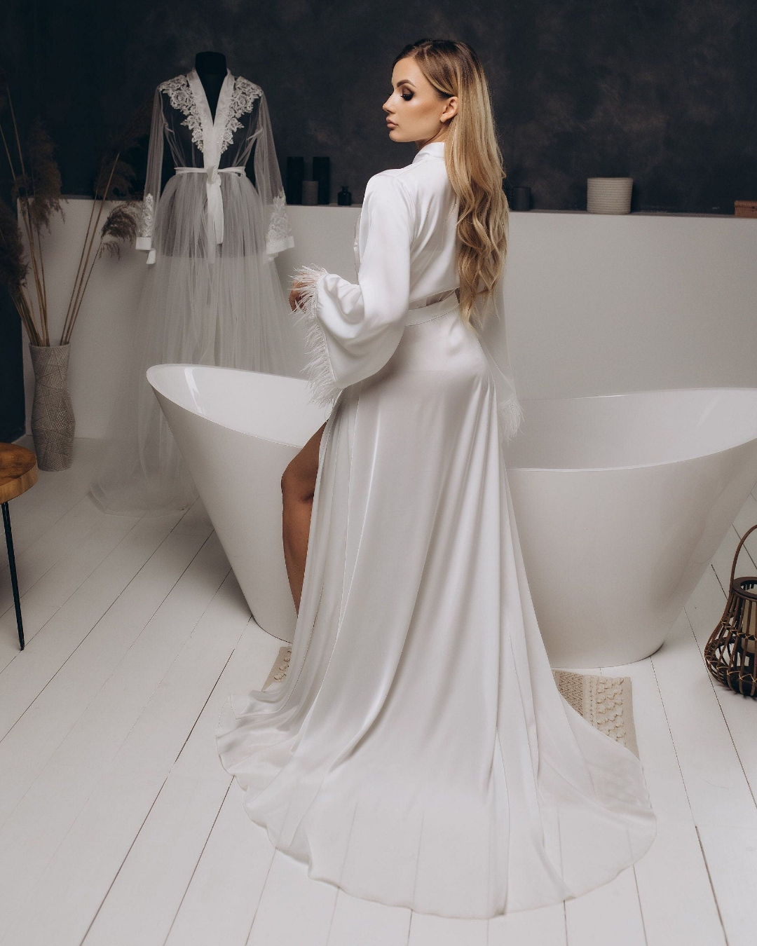 a woman in a white robe standing next to a bathtub