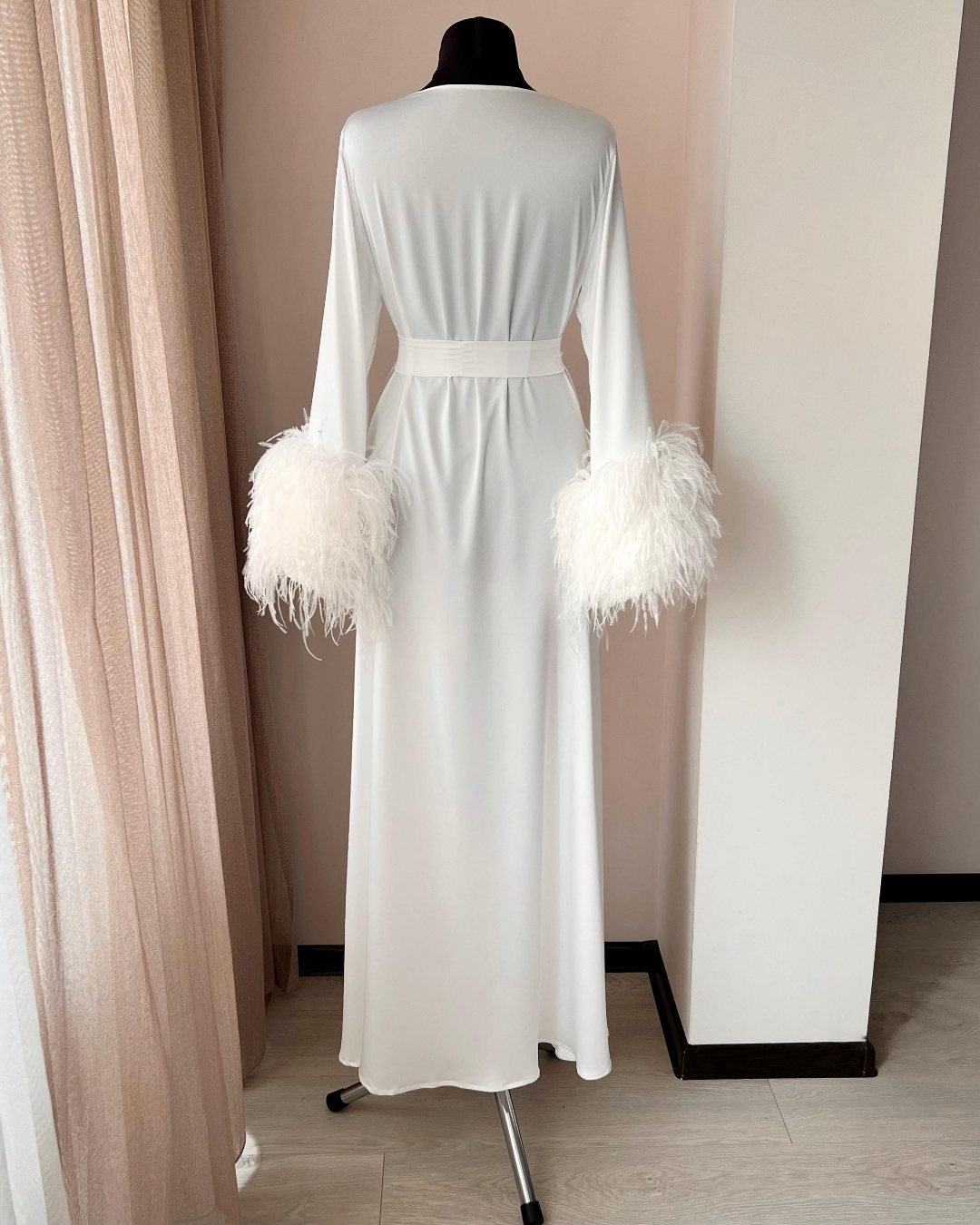 a white robe with feathers on the sleeves