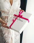 a woman holding a white box with a pink ribbon