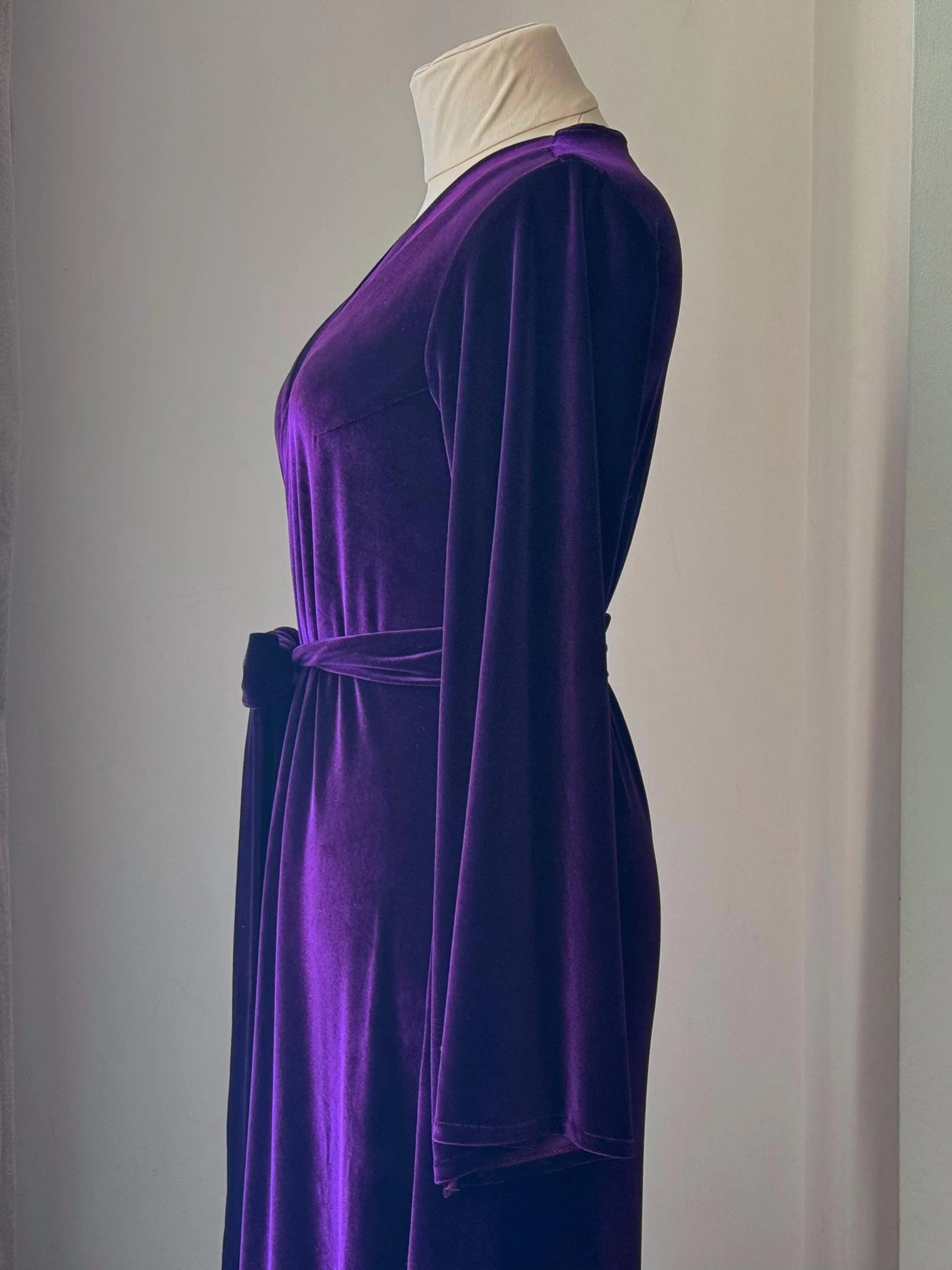 Close-up side view of purple velvet robe showing soft drape and kimono-style sleeve.