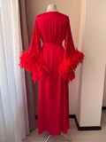 A red, long dress with feather sleeves displayed on a mannequin.