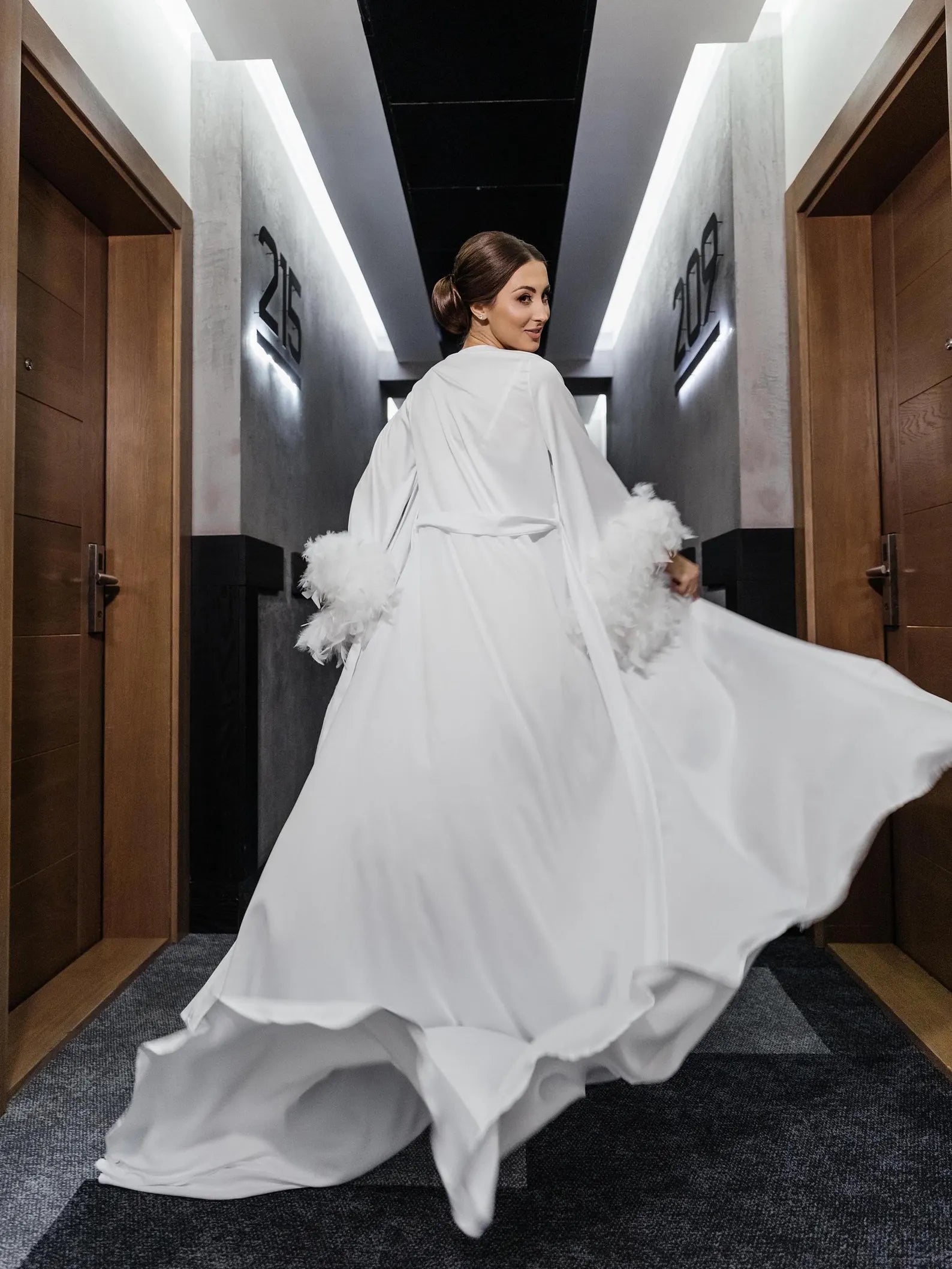 a woman in a white dress is walking down a hallway