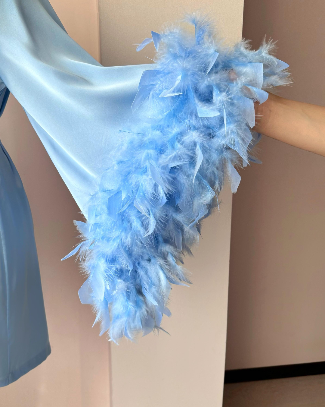 a woman's hand holding a blue feathered dress