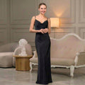 Woman wearing a long black satin slip dress with thin straps