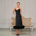 Woman wearing a black satin slip dress with feather hem and cowl neck