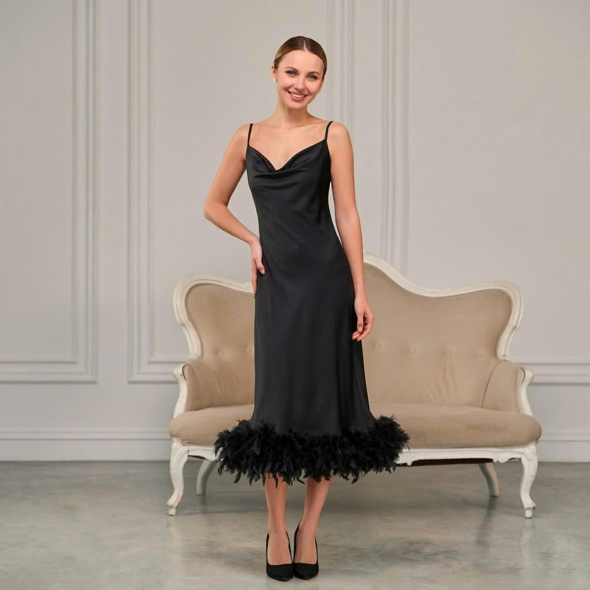 Woman wearing a black satin slip dress with feather hem and cowl neck