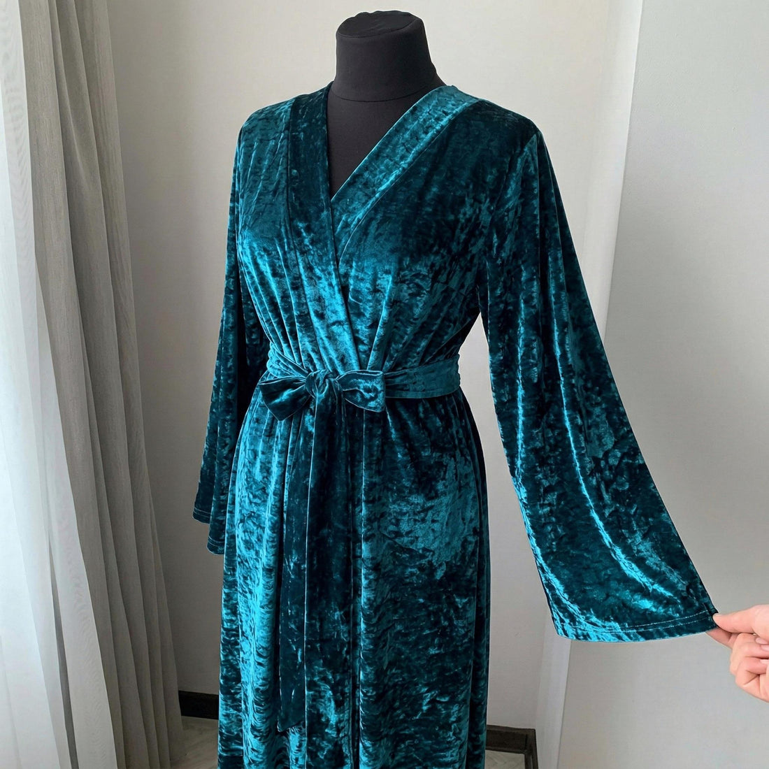 Woman wearing a long teal crushed velour robe in a floor-length wrap silhouette