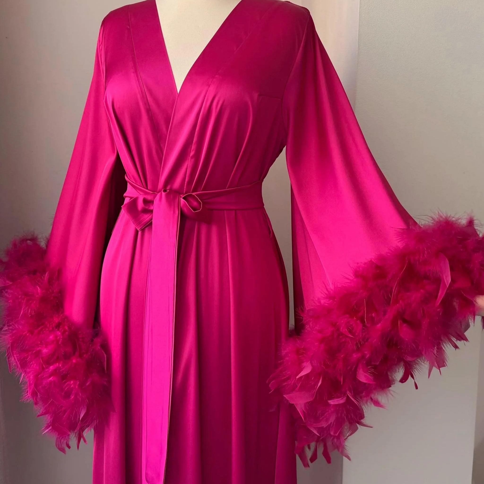 Hot pink satin dressing gown with flowing sleeves and fluffy double feather trim.