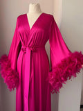 Hot pink satin dressing gown with flowing sleeves and fluffy double feather trim.