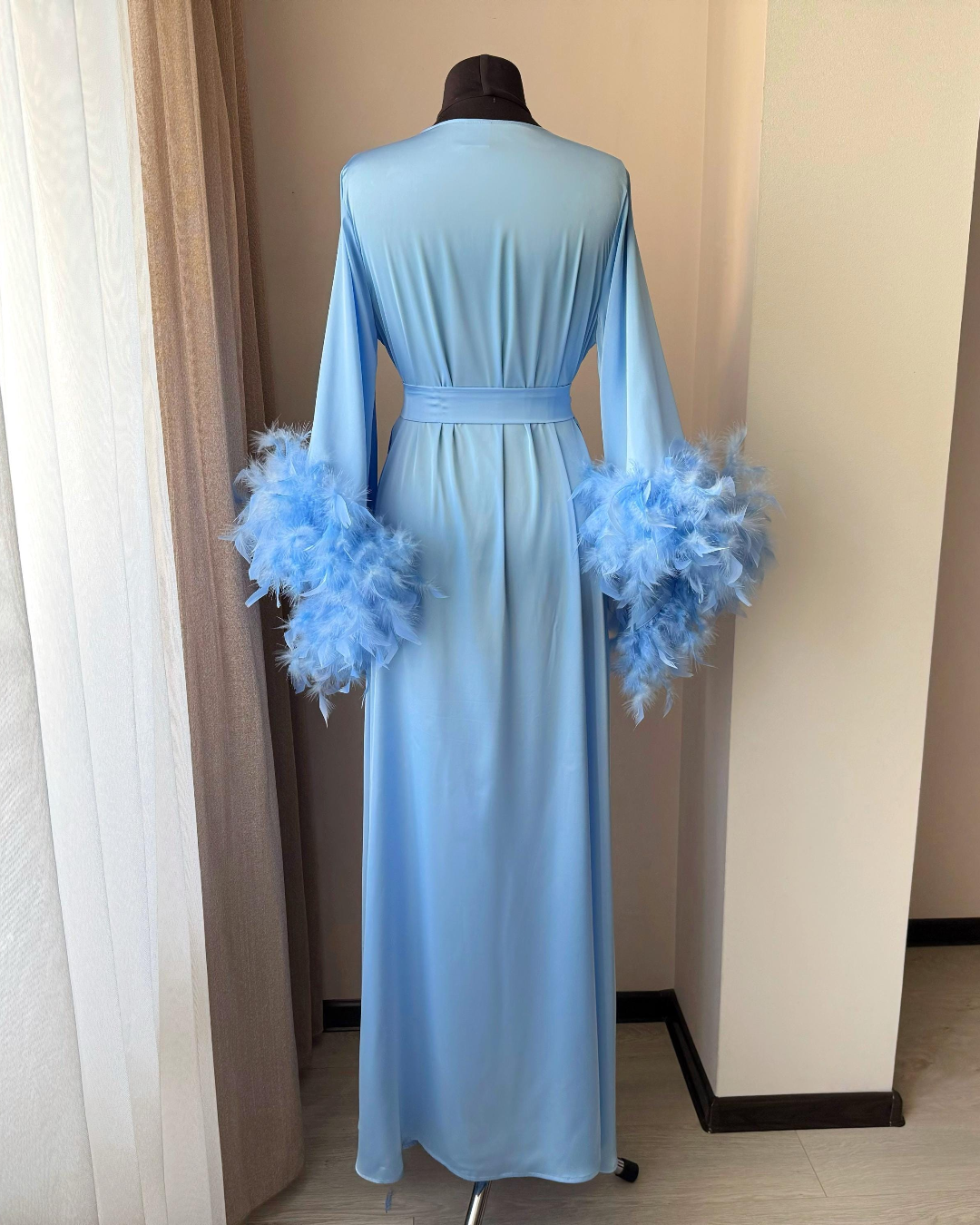 a blue dress with feathers on the sleeves