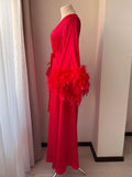 A mannequin wearing a long red dress with a large feather boa draped over the shoulder.