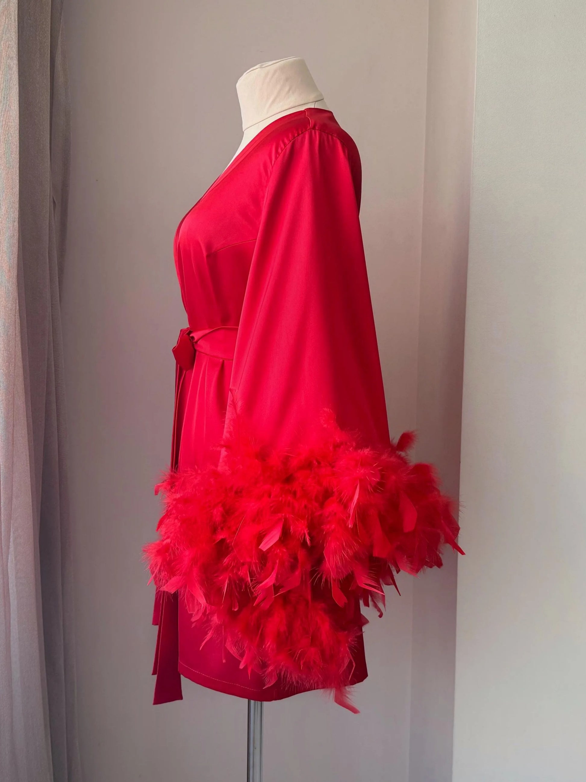 A mannequin wearing a red kimono with a large feather boa draped over the shoulder.