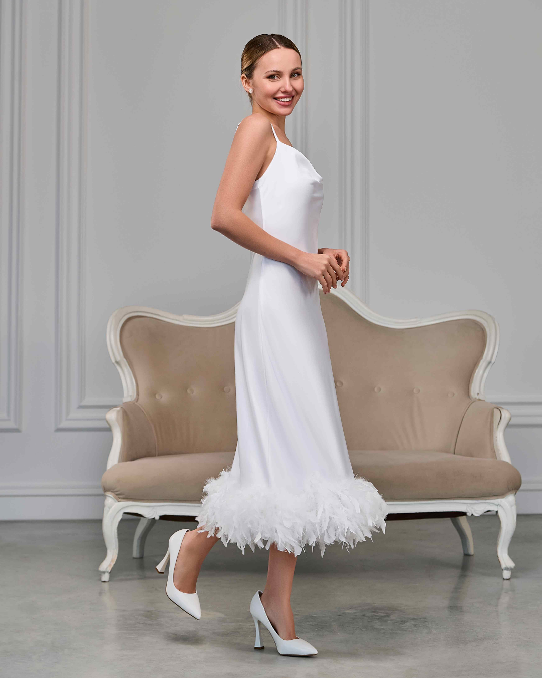 Side view of bride in satin white feather nightgown, smiling and walking gracefully