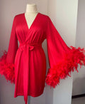 A red satin robe with long sleeves and feather accents displayed on a mannequin.