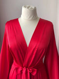 A mannequin wearing a bright red satin robe with a white collar.