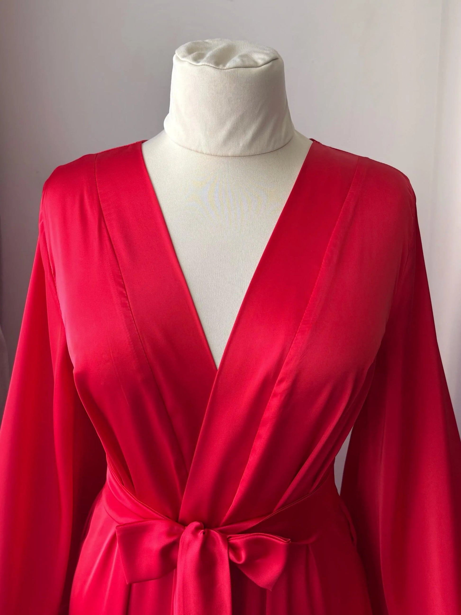 A mannequin wearing a bright red satin robe with a white collar.