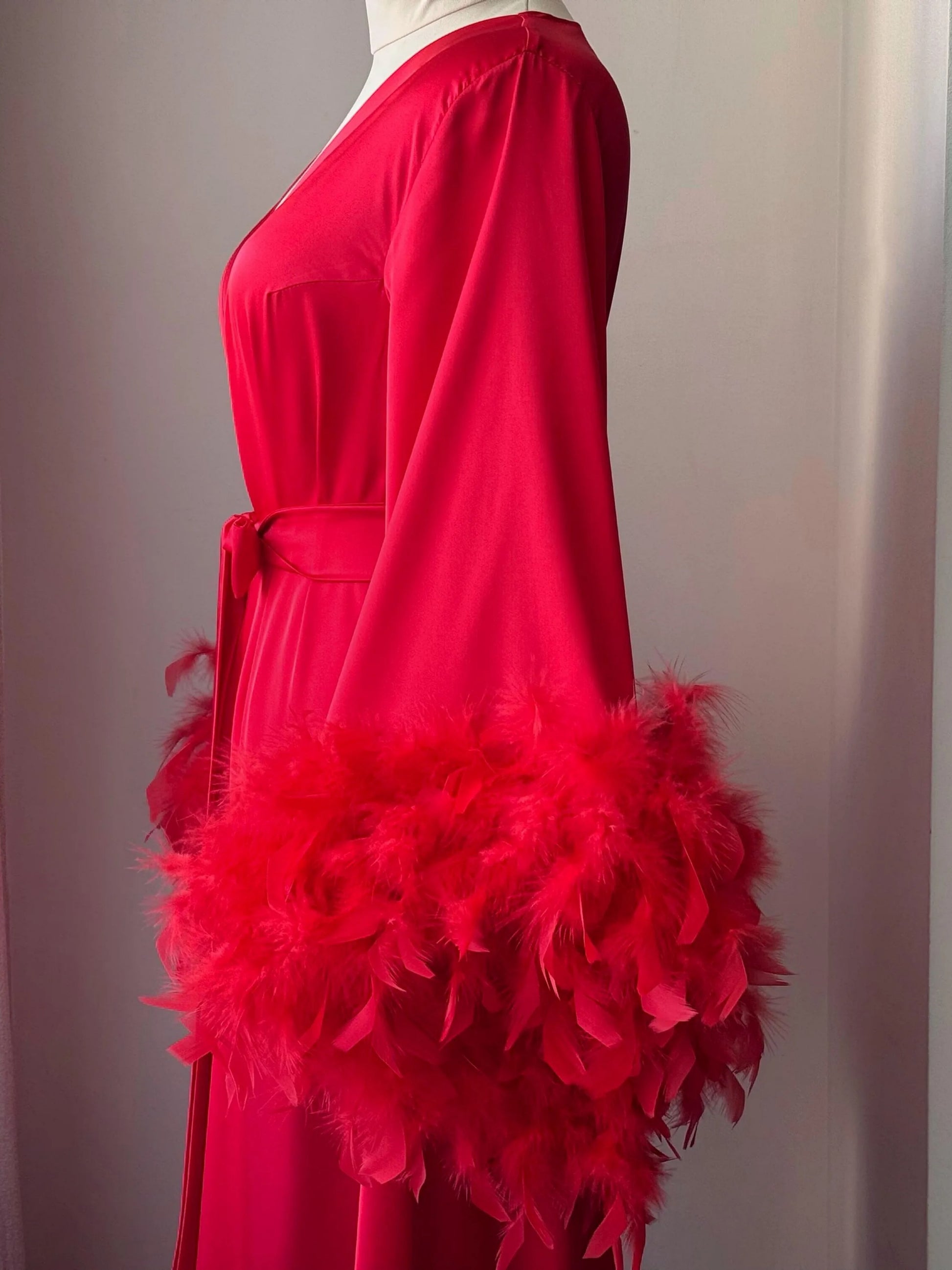 A red dress with long sleeves and a feathery trim, displayed on a mannequin.