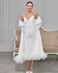 White satin bridal nightgown and sheer robe with ostrich feather cuffs and hem, bride smiling in soft light
