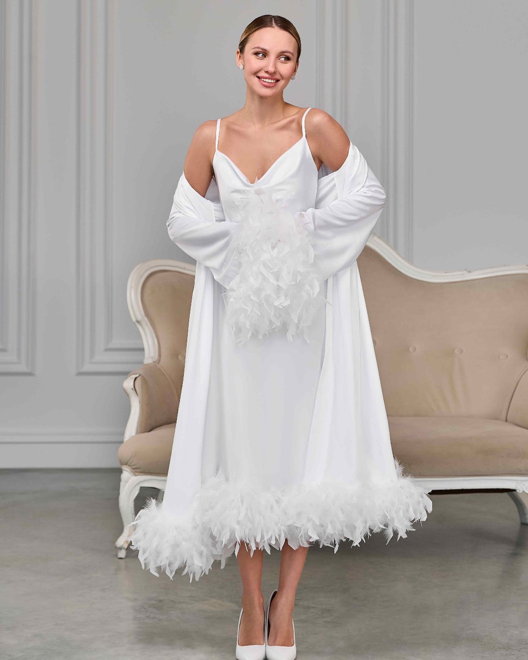 White satin bridal nightgown and sheer robe with ostrich feather cuffs and hem, bride smiling in soft light