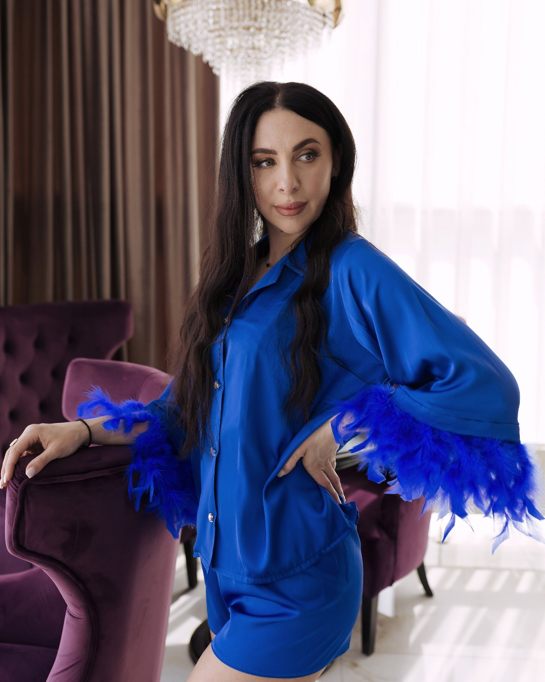 a woman in a blue dress standing next to a purple chair