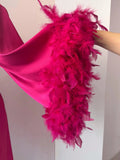 A close-up view of a vibrant pink feathered accessory, such as a shawl or cape, with a large amount of feathers attached to it.