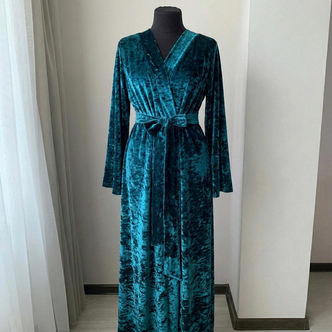 Woman wearing a long teal crushed velour robe in a floor-length wrap silhouette