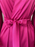 A close-up view of a bright pink satin robe with a bow at the waist.