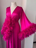 A mannequin wearing a long, pink satin dress with a feathery collar and sleeves.