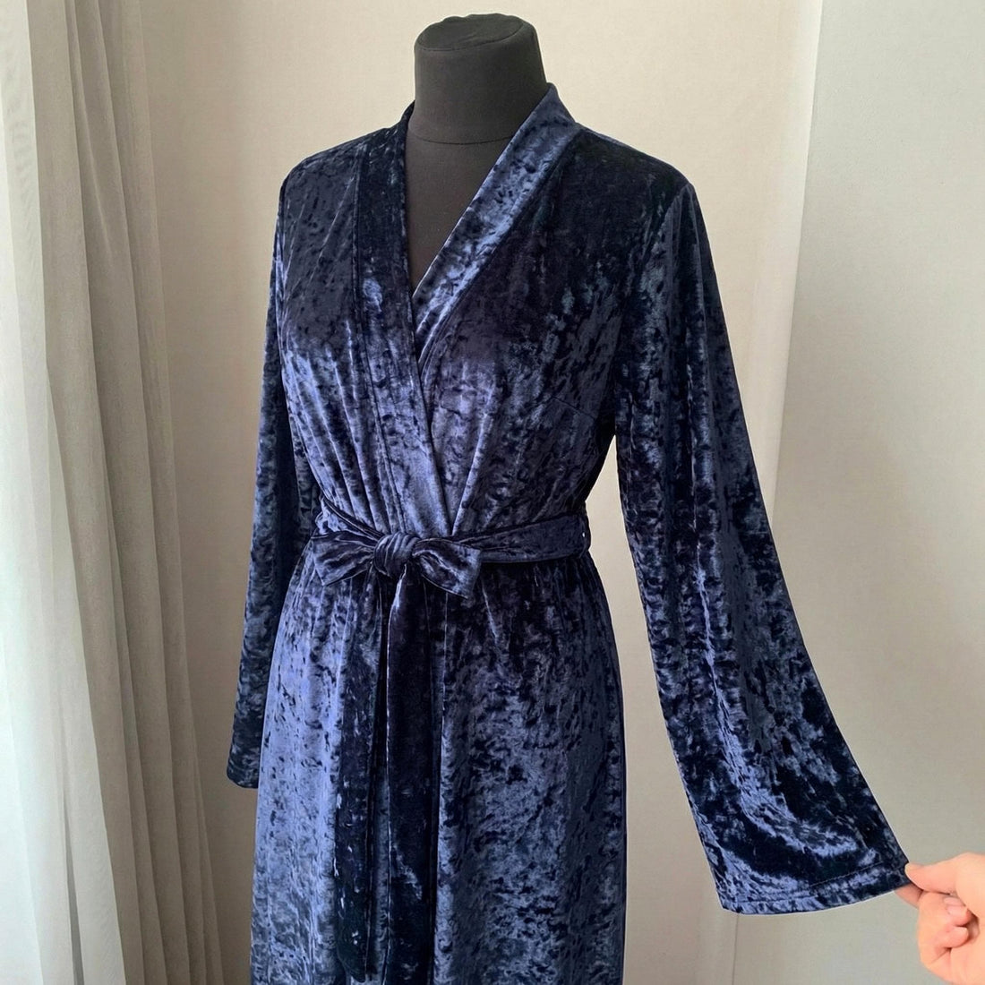 Woman wearing a long midnight blue crushed velvet robe in a floor-length wrap silhouette