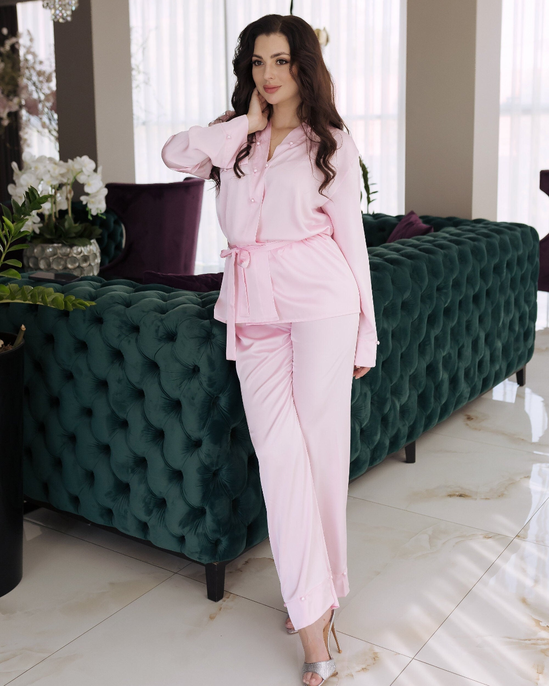 a woman in a pink suit standing next to a green couch