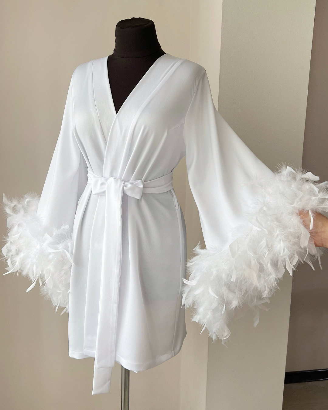 a white robe with feathers on a mannequin