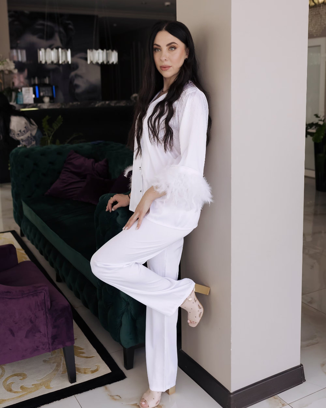 a woman leaning against a wall in a white outfit