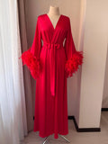 A red satin robe with long sleeves and feather accents, displayed on a mannequin.
