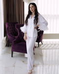 a woman in a white outfit standing in front of a purple chair