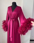 Pink dress with feathered sleeves on a mannequin against a white background