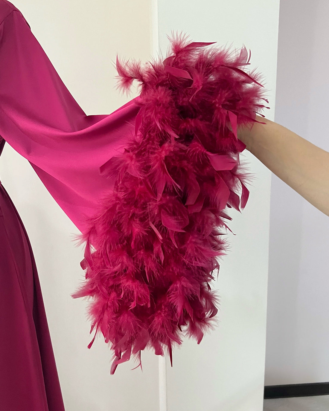 Pink dress with feathered sleeves on a mannequin against a white background