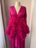 A mannequin wearing a long, pink dress with a large amount of pink feathers draped over it.
