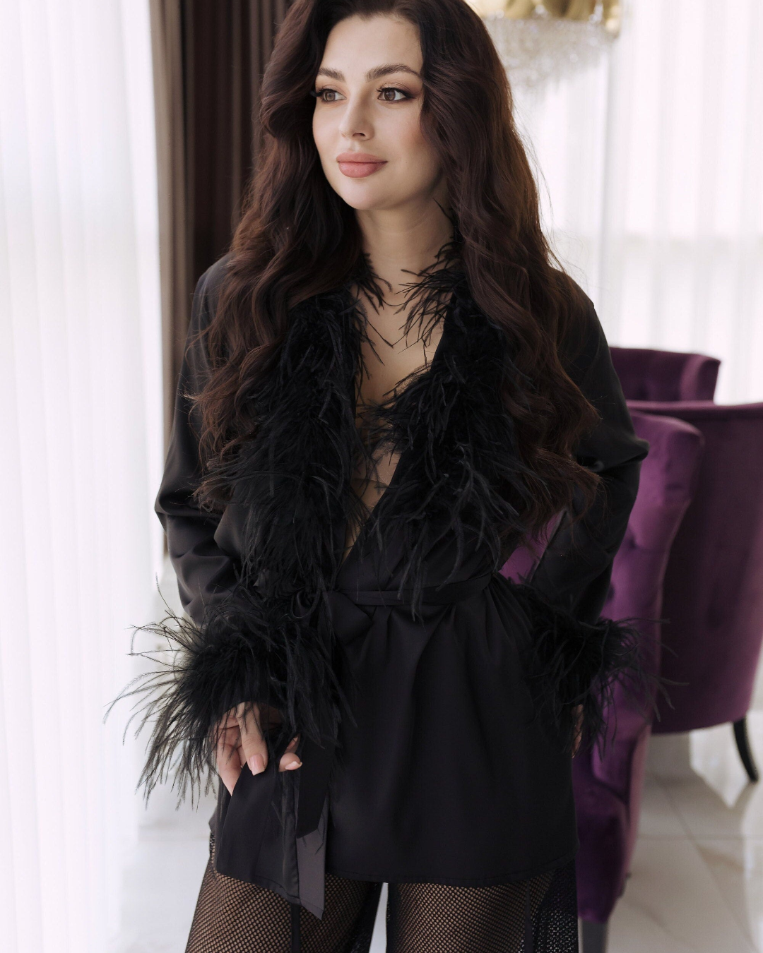 a woman in a black dress standing next to a purple chair