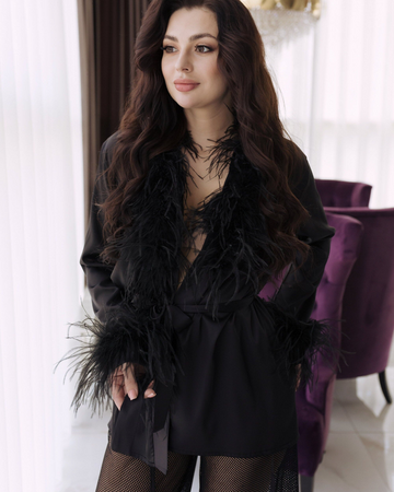 Model wearing black feather-trimmed satin pajama top with sheer mesh pants