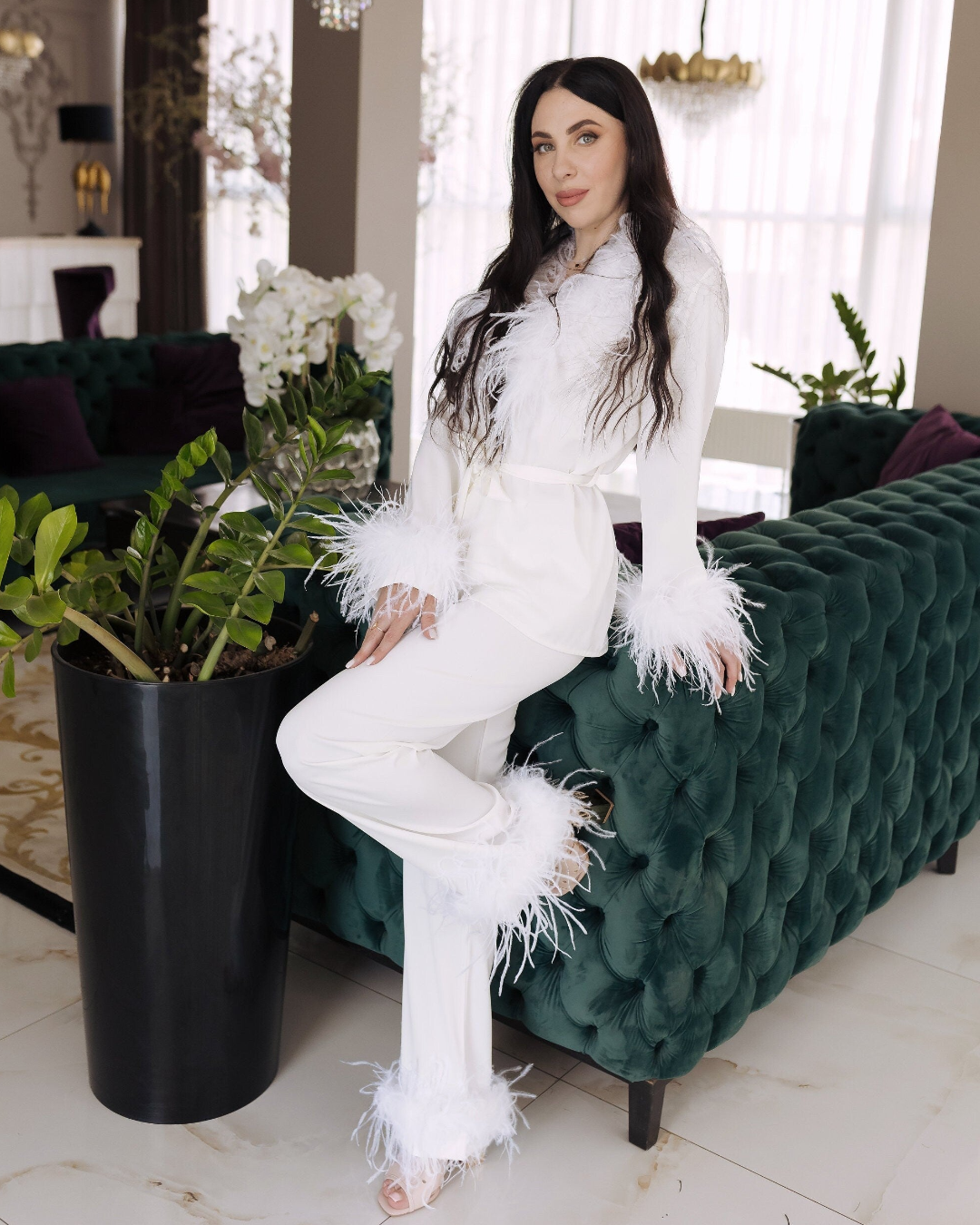 a woman sitting on a green couch next to a potted plant