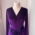 Close view of wrap-front design and tied belt on luxurious purple velvet long robe.