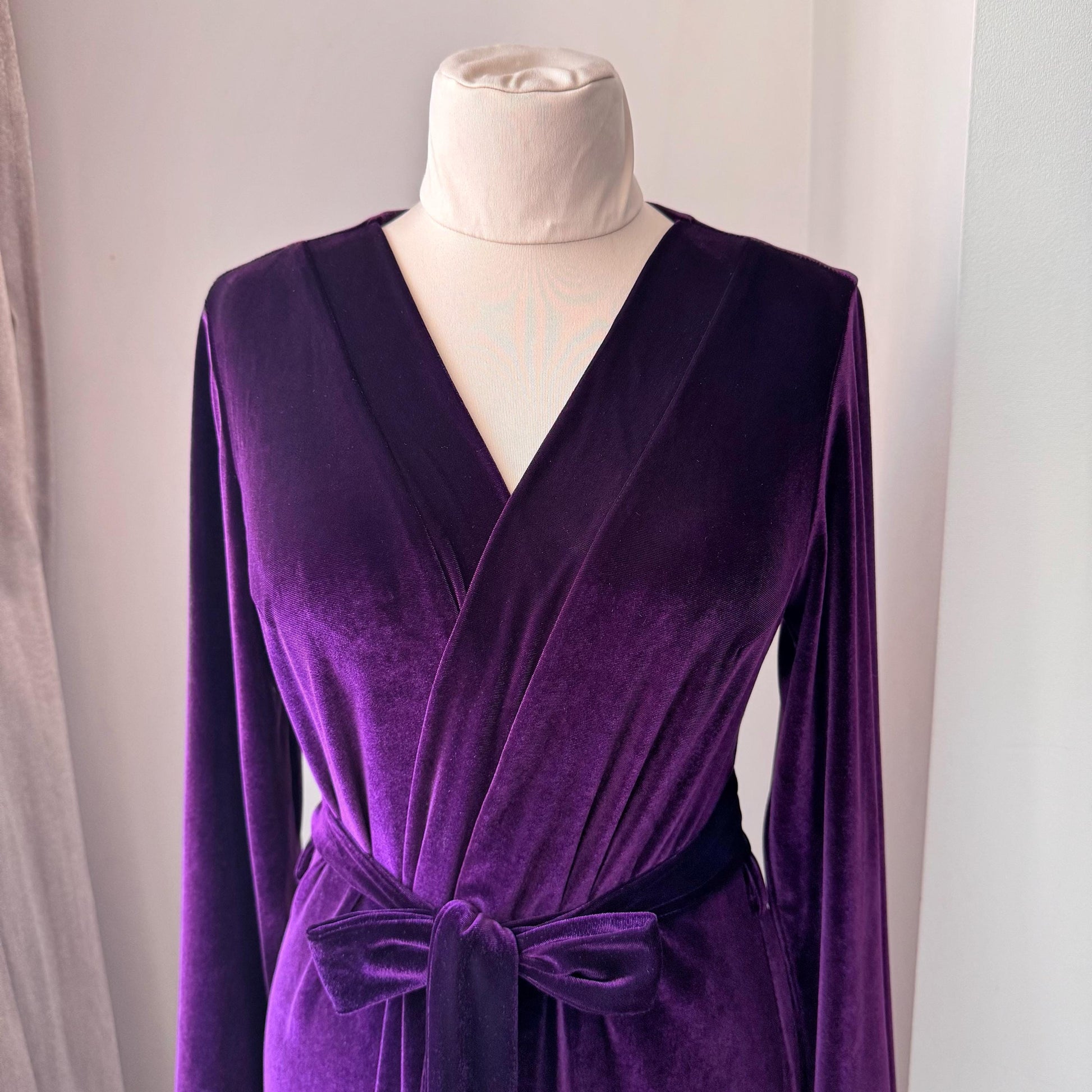 Close view of wrap-front design and tied belt on luxurious purple velvet long robe.