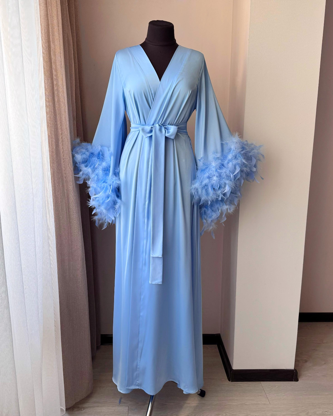 a blue robe on a mannequin next to a window