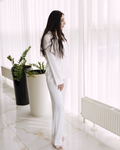 a woman standing in front of a window next to a plant