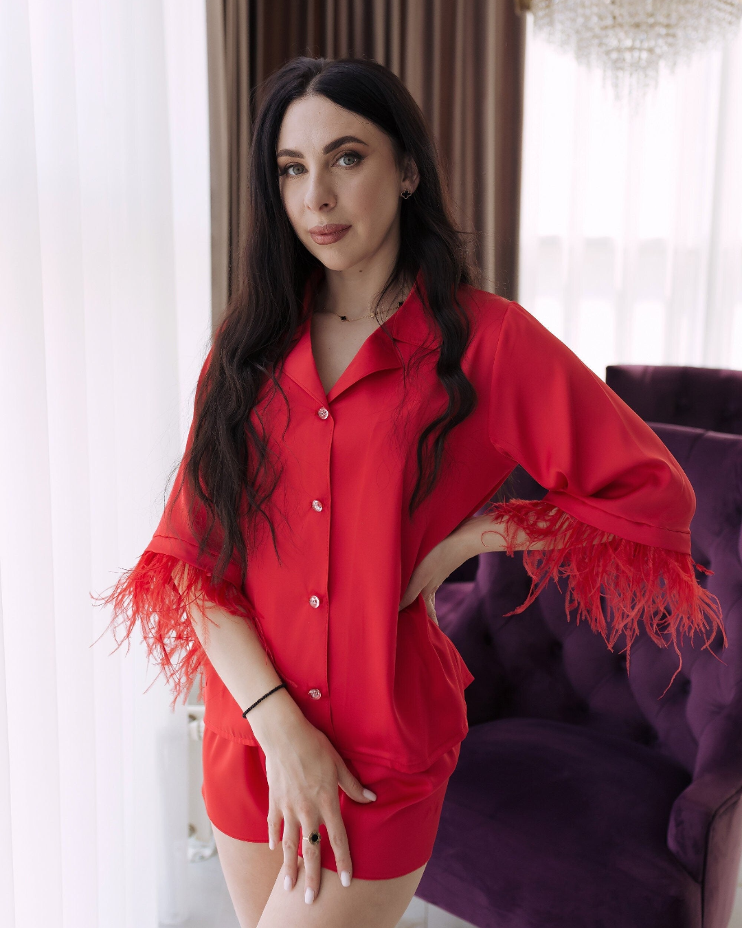 a woman in a red shirt and shorts posing in front of a purple chair