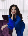 a woman in a blue dress leaning on a purple chair