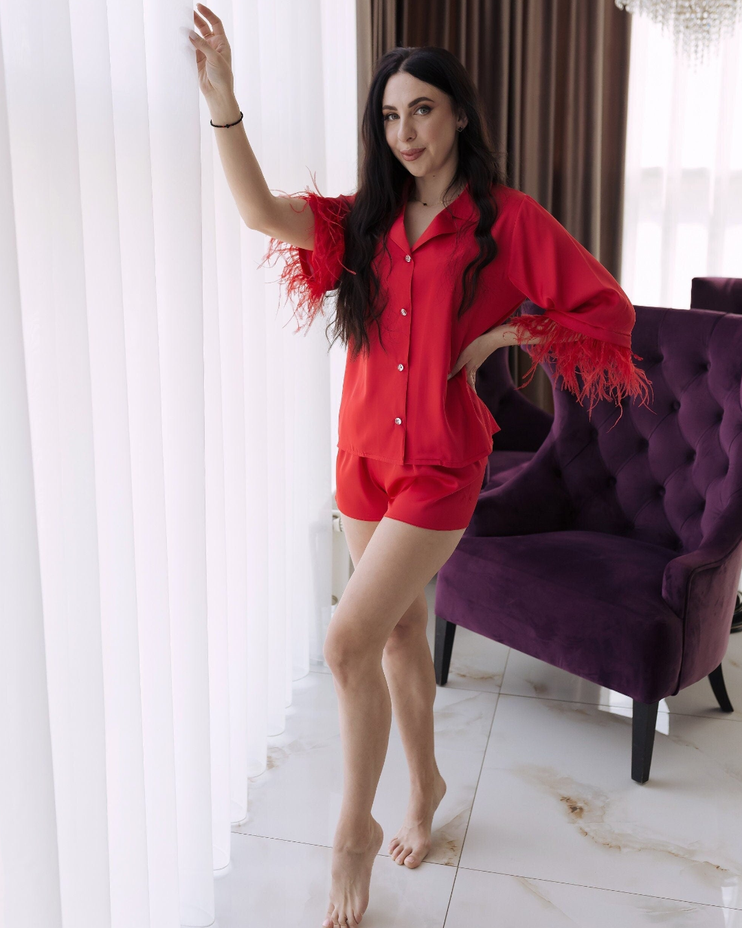 a woman in a red shirt and shorts posing in front of a purple chair