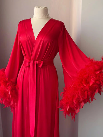 A red satin robe with long sleeves and feather accents, displayed on a mannequin.
