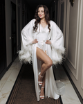 a woman in a white robe and high heels posing for a picture