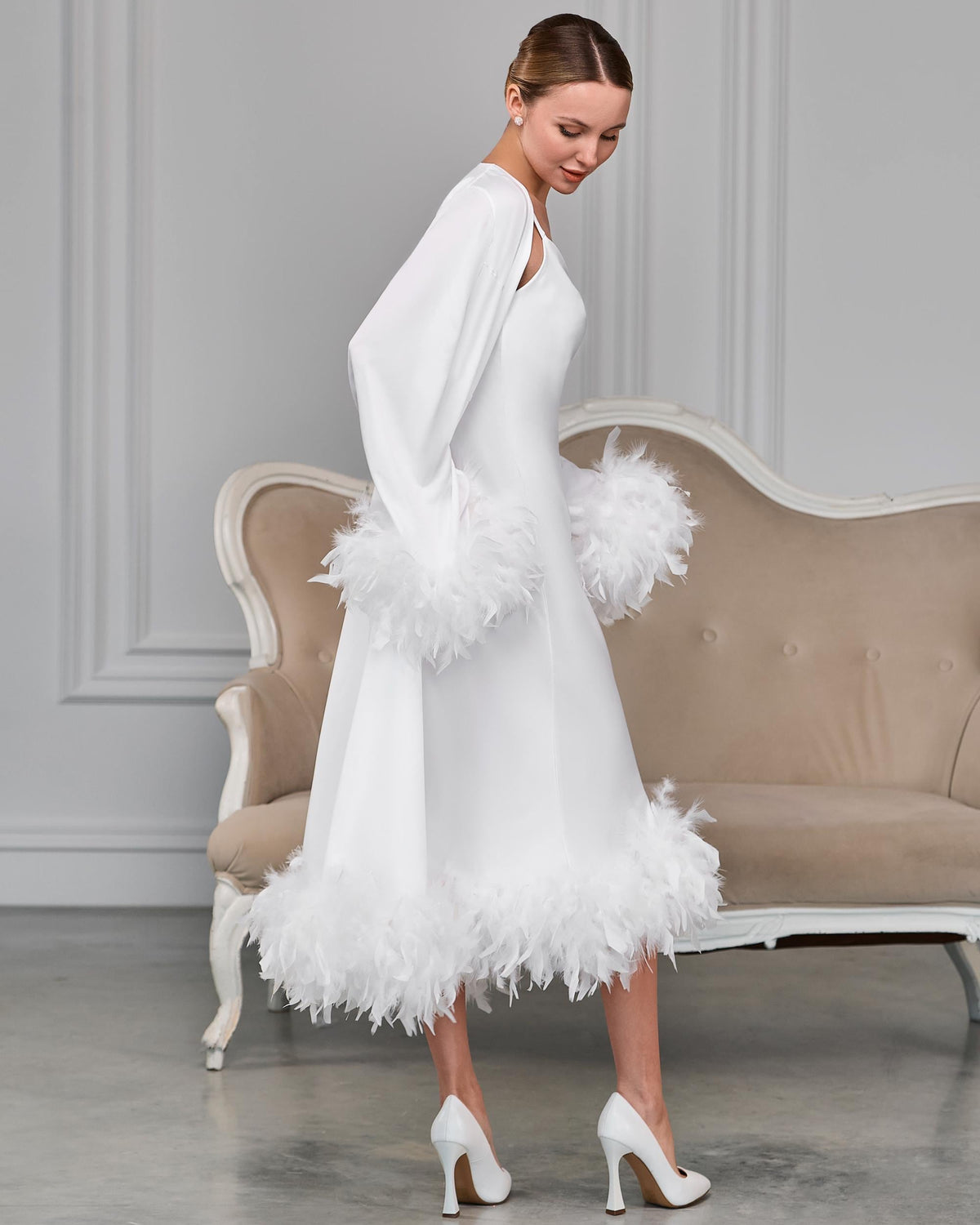Side view of white satin bridal robe with feather trim on the cuffs and hem